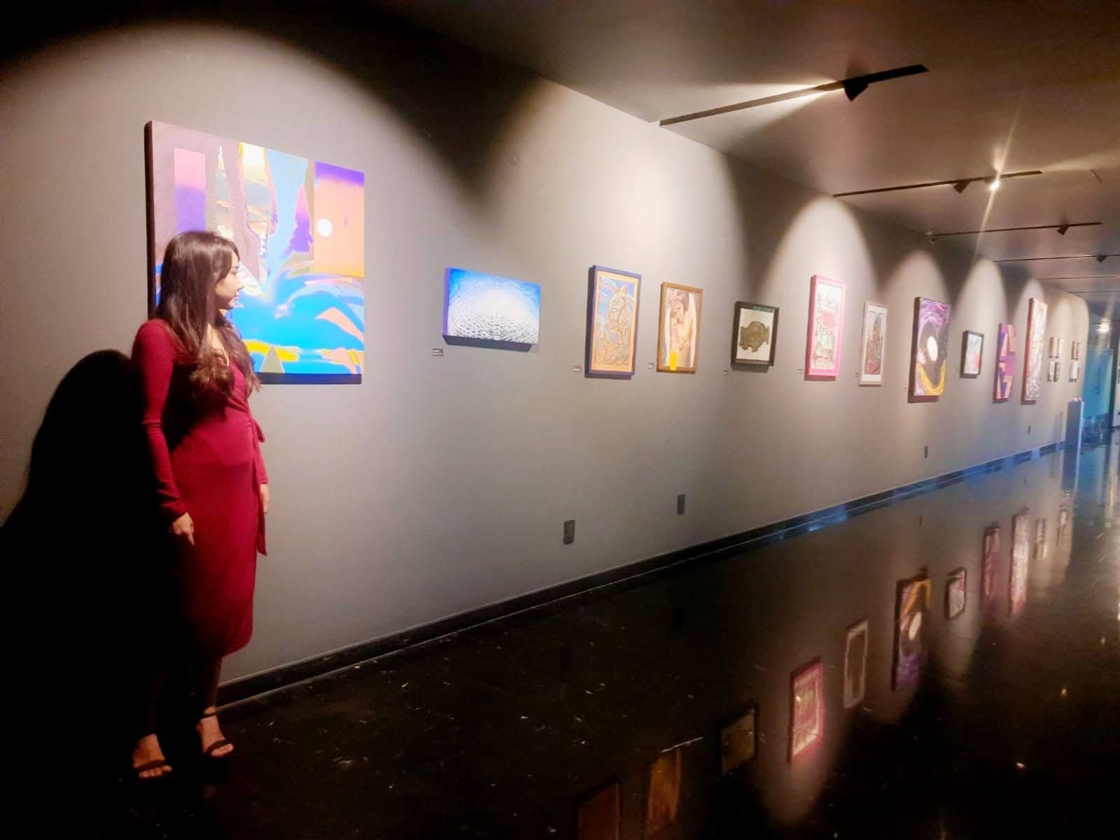 Paola Hernández observando su obra en una exhibición de galería