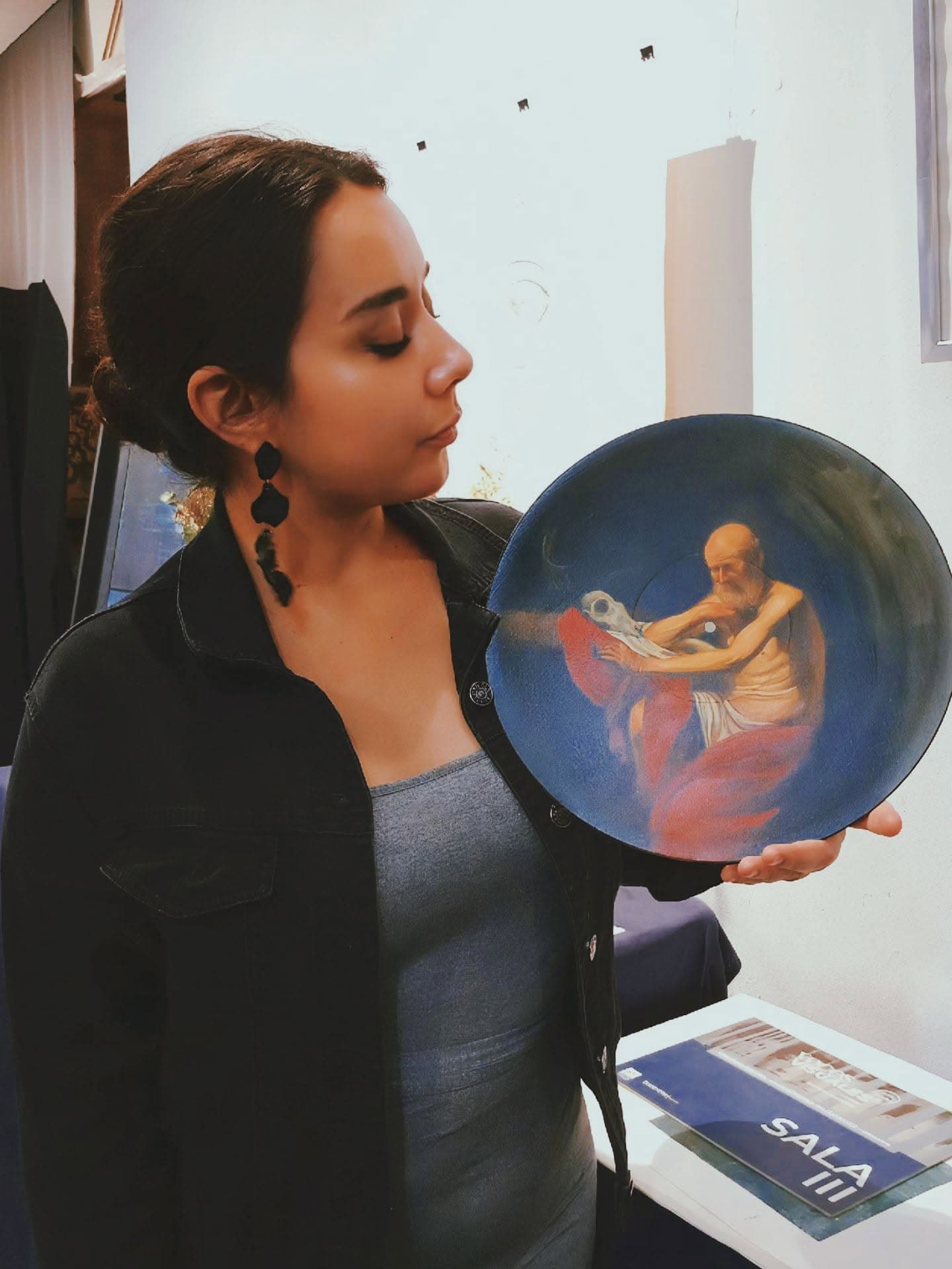 Retrato de estudio de Paola Hernández sosteniendo una de sus obras
